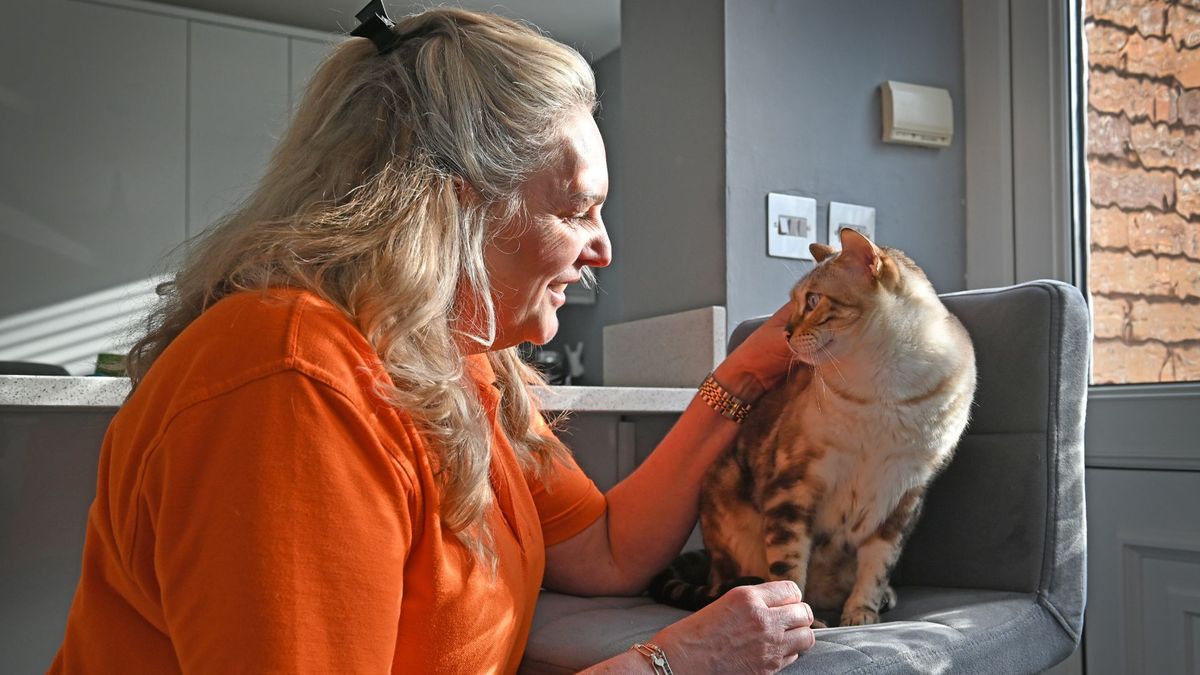 Amanda stroking her cat who sits on a chair