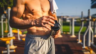 Muscled man holding a protein shaker outdoors