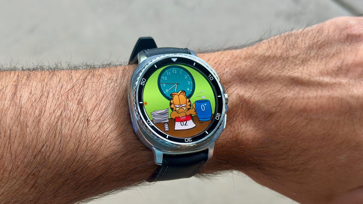 The Samsung Galaxy Watch 8 Classic on a person's wrist, showing a custom watch face from Facer with Garfield.