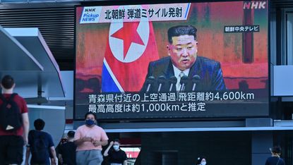 Pedestrians in Tokyo walk under a large video screen showing images of North Korea’s leader Kim Jong Un 