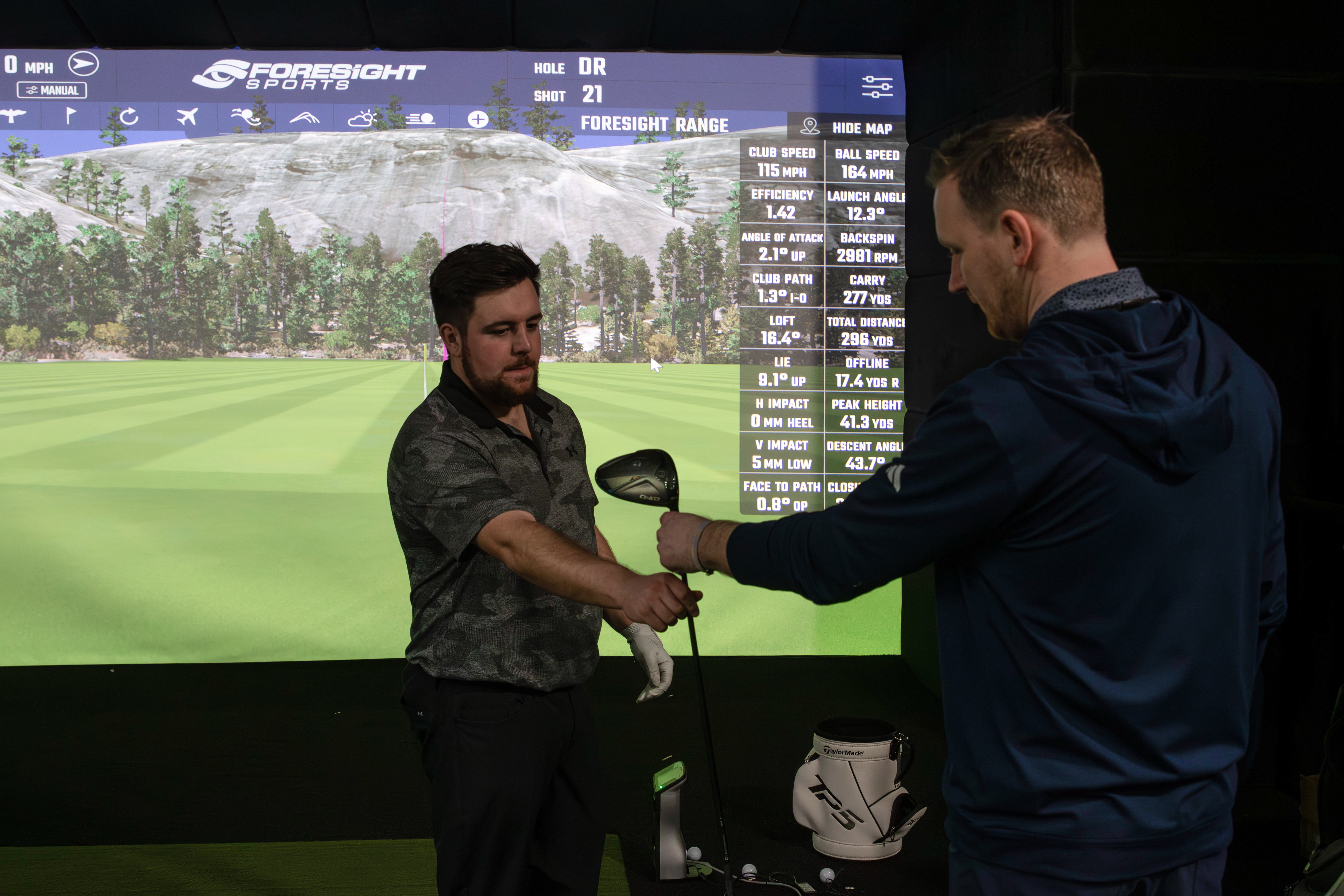 A fitter hands a golf club to a golfer