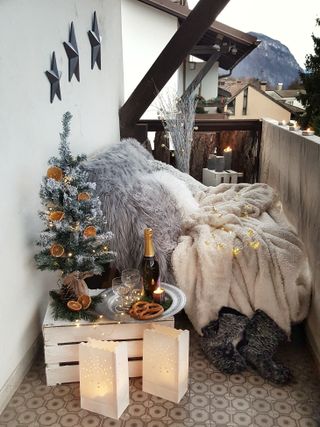 festive balcony with lots of grey throws and cushions and a Christmas tree