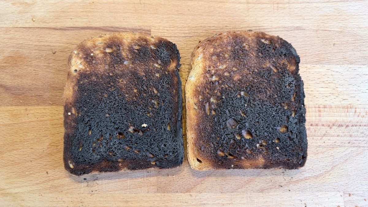 Two slices of burned toast on a wooden board after cooked in the KitchenAid Pro Line toaster