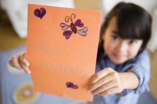 A child holding up mother's day card illustrating Mother's Day origins