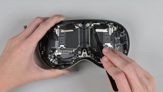 A teardown of the Apple Vision Pro headset, showing a person unscrewing various components of the device.