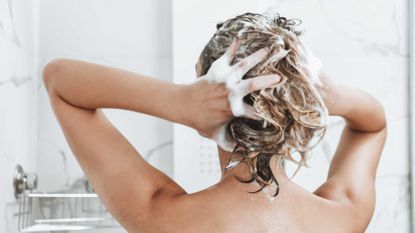 woman shampooing her hair in a white shower