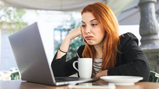 Young woman using laptop, looking annoyed