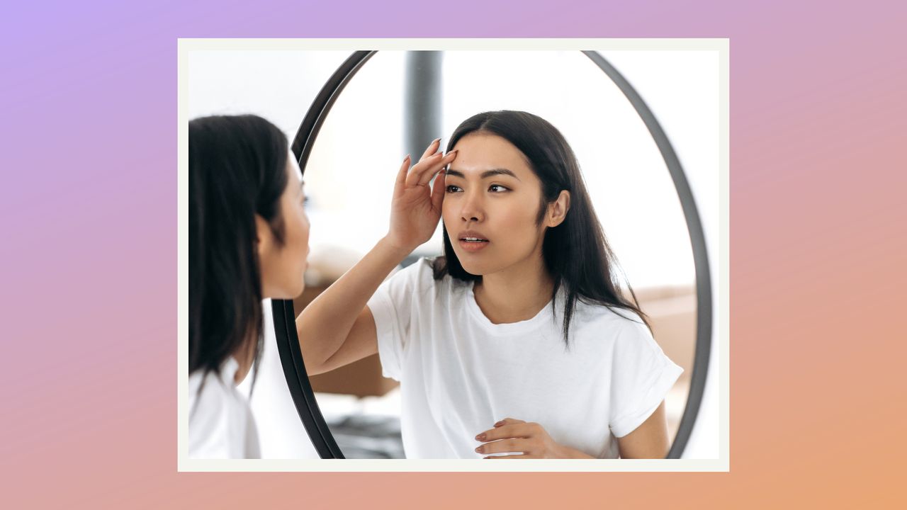 woman looking at skin in mirror