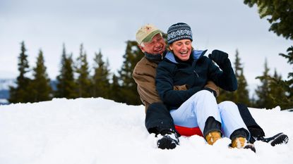 Senior couple sit on a sled in the snow on a Colorado mountain