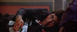 Tony Montana (Al Pacino) seeks cover behind a corpse long enough to load a grenade in