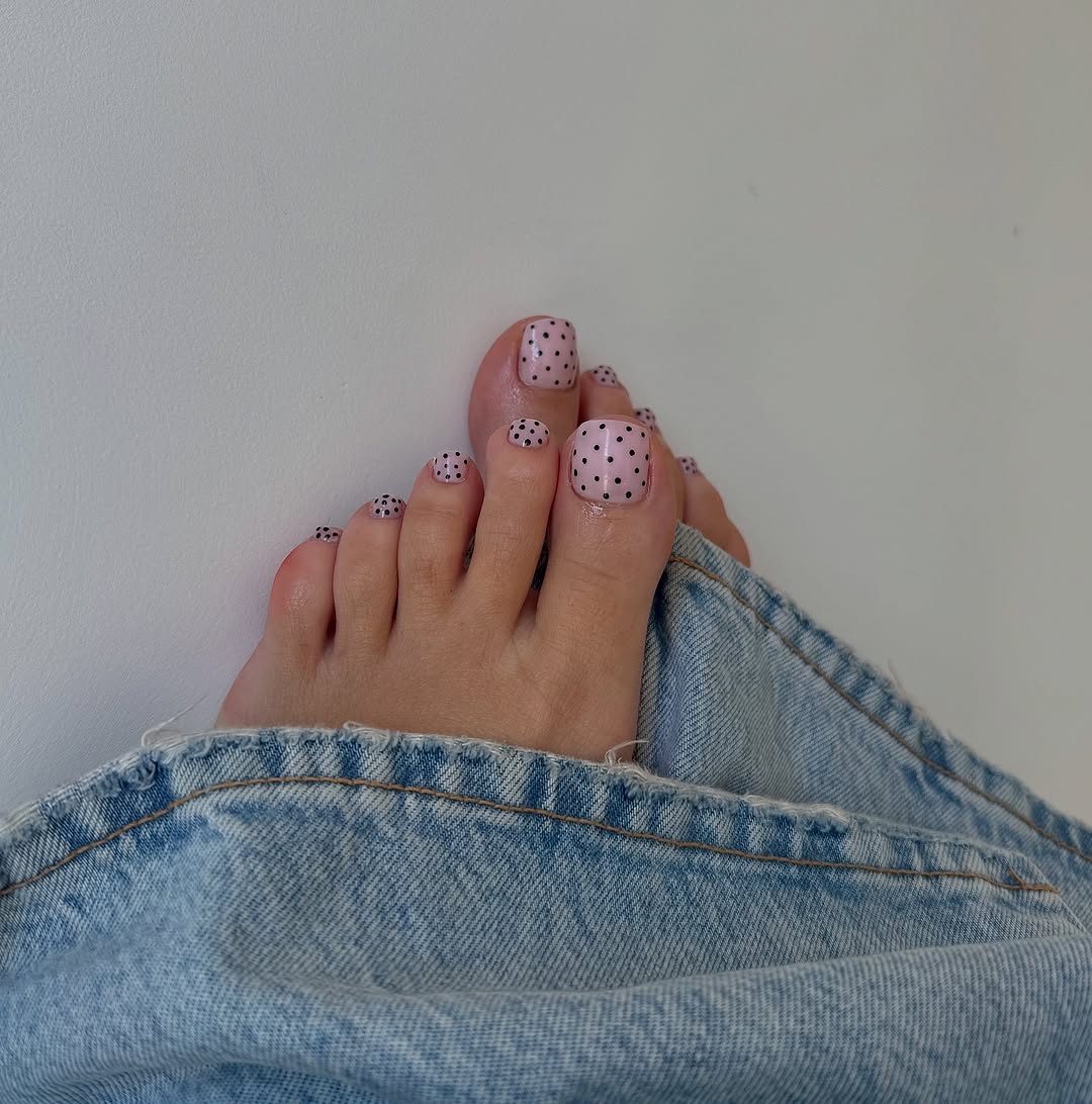 pink polka dot pediure on feet poking out of jeans