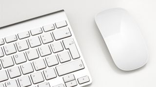 The Apple Magic Mouse on a white surface next to the Magic Keyboard.