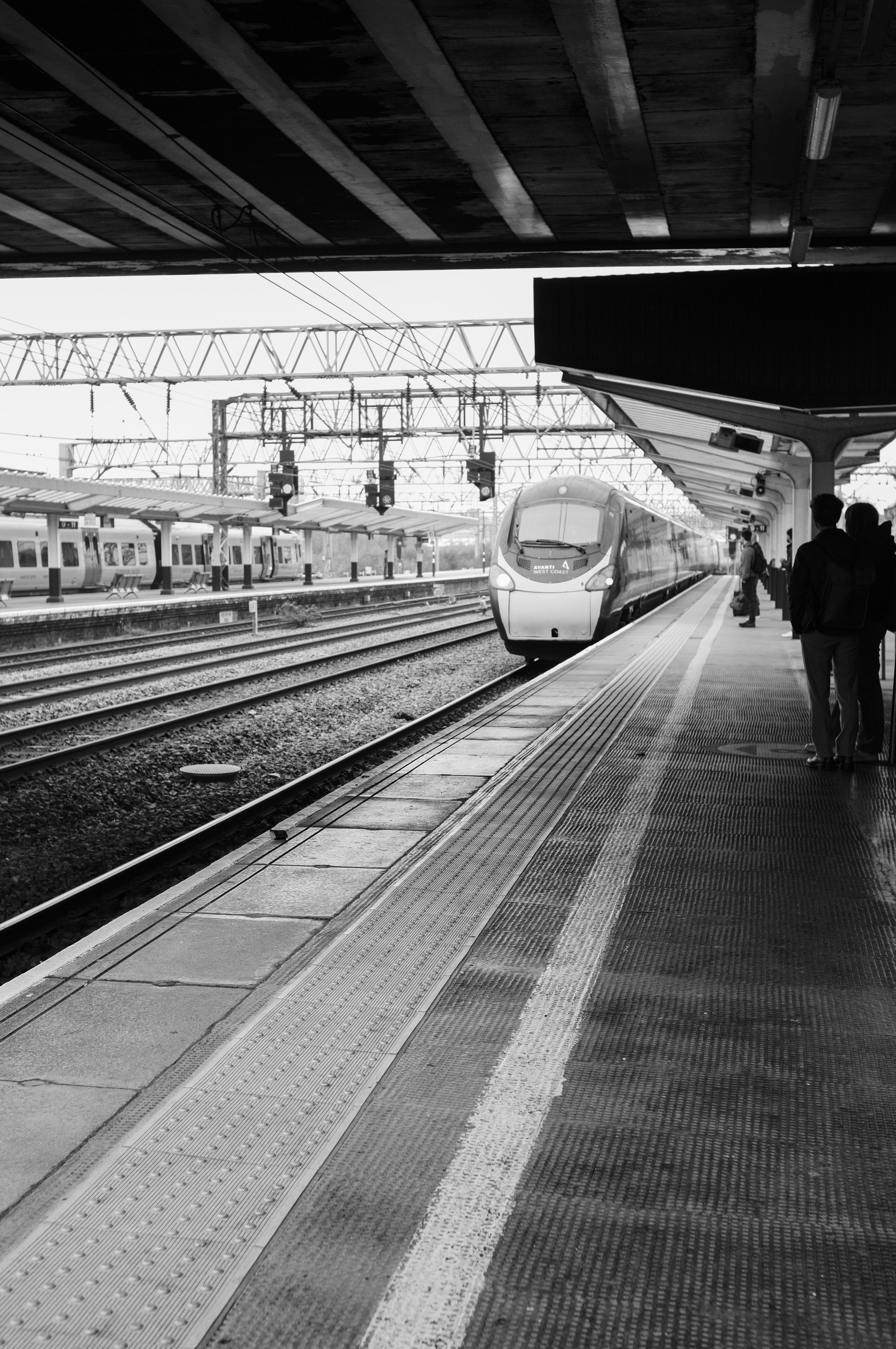 A train pulling into the station as people wait to board