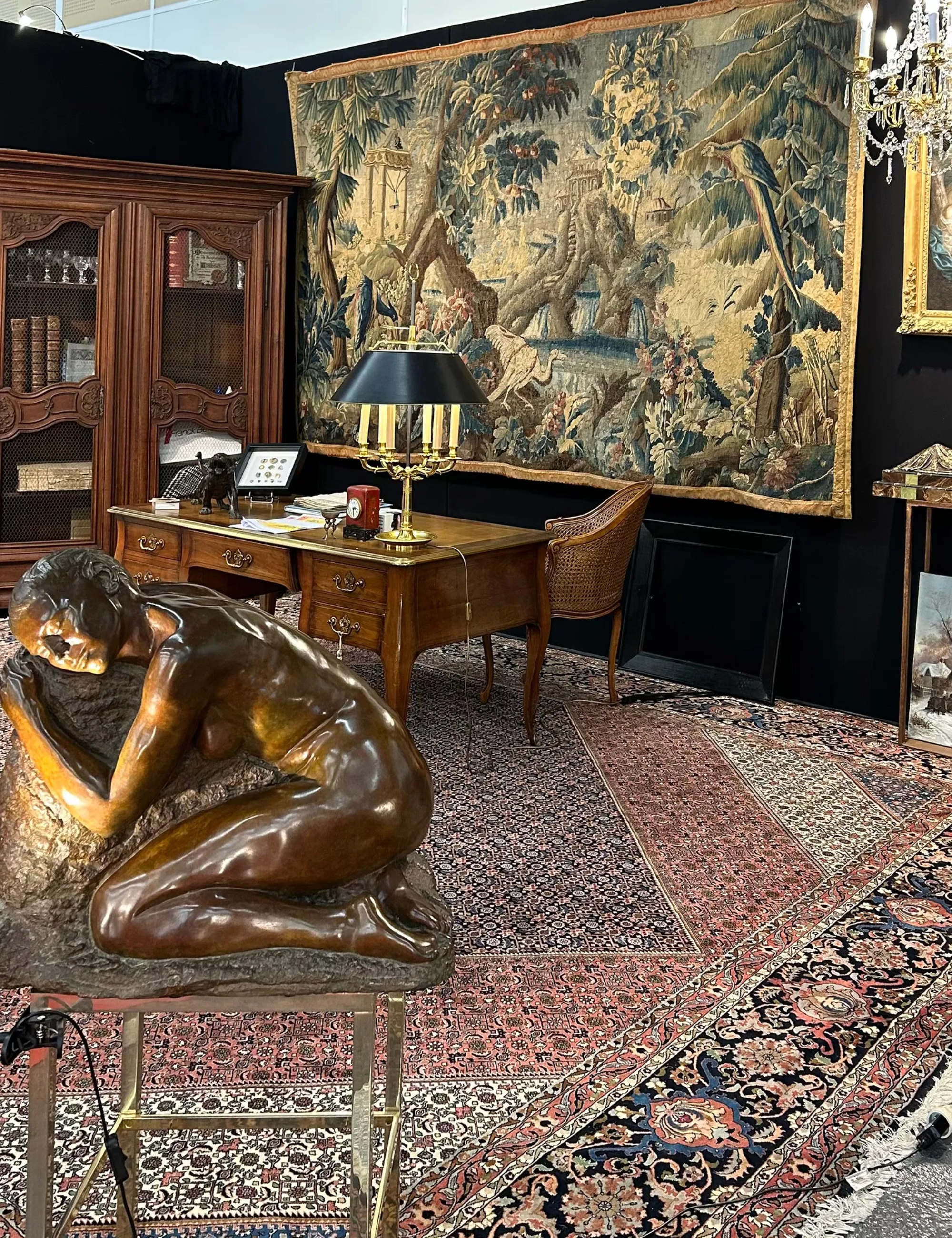 Antique wall tapestry hanging in an auction stall styled with various collectibles