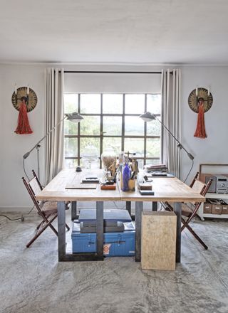 sewing/craft room with two tables joined together by window, matching chairs, lamps and wall lights, storage, gray floor