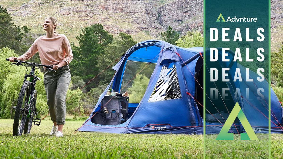 Woman pushing bike beside Berghaus tent