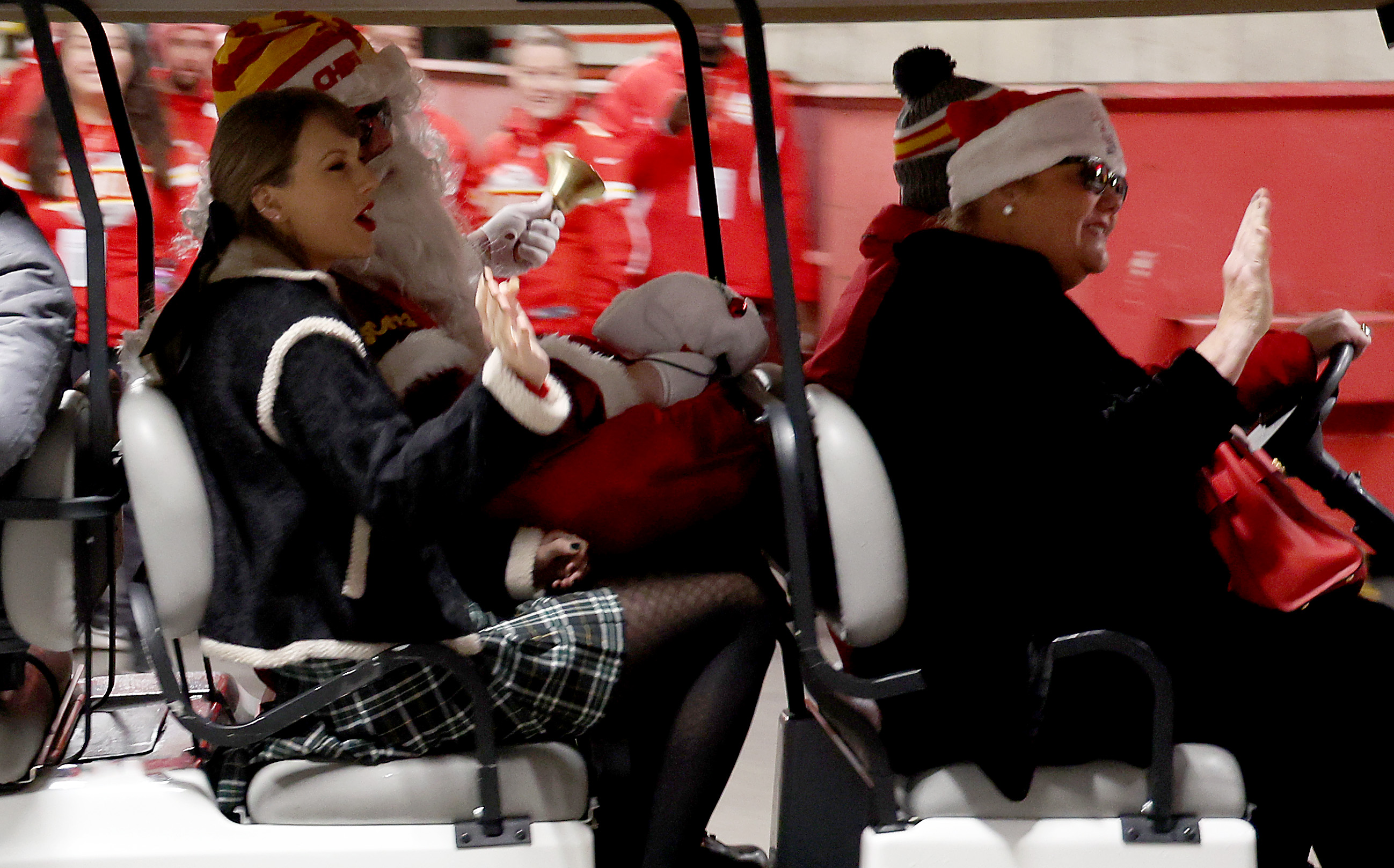 Taylor Swift riding a golf cart wearing a plaid skirt and hair bow on Christmas