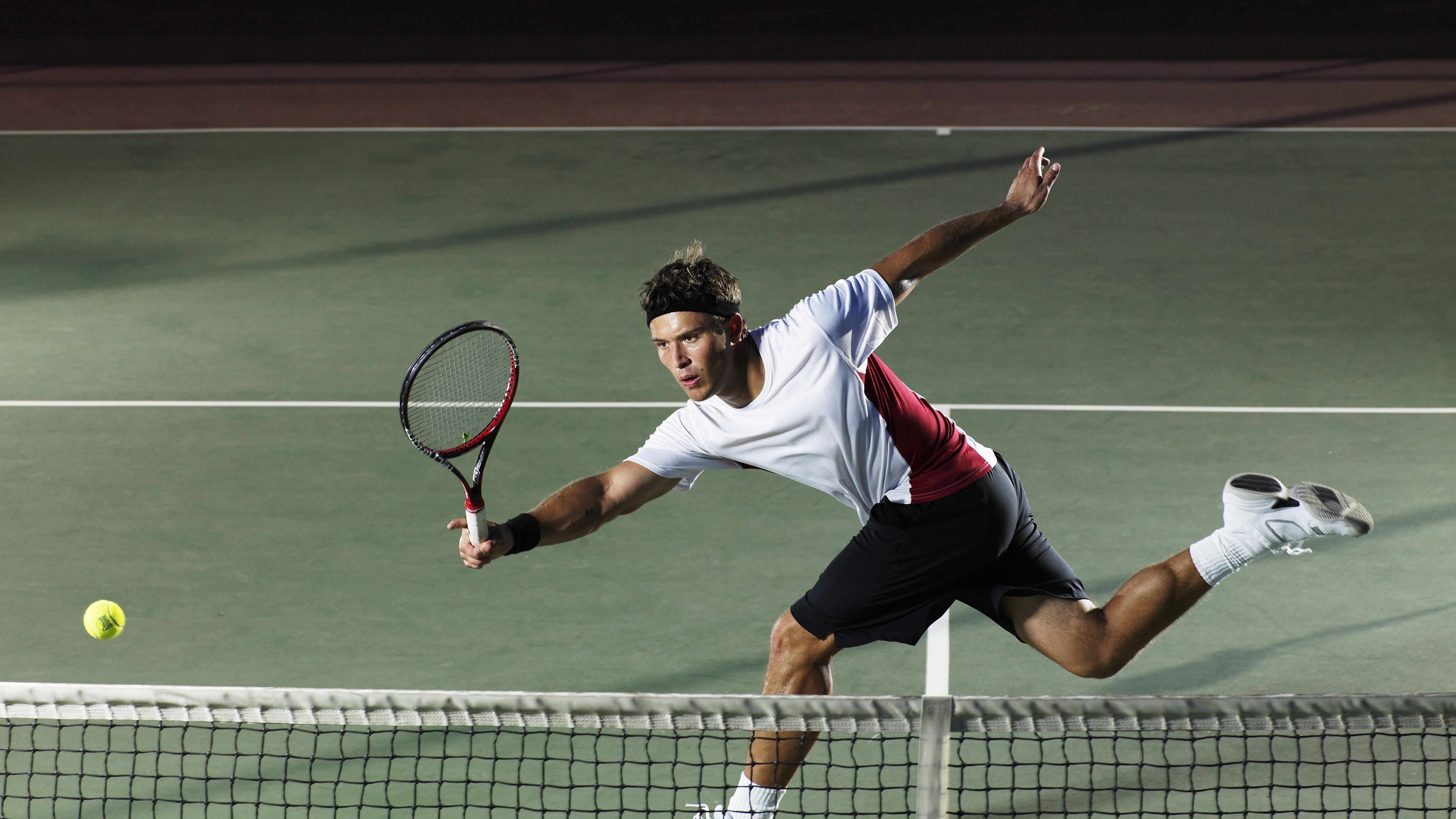 Hombre corriendo para golpear una pelota de tenis con una raqueta