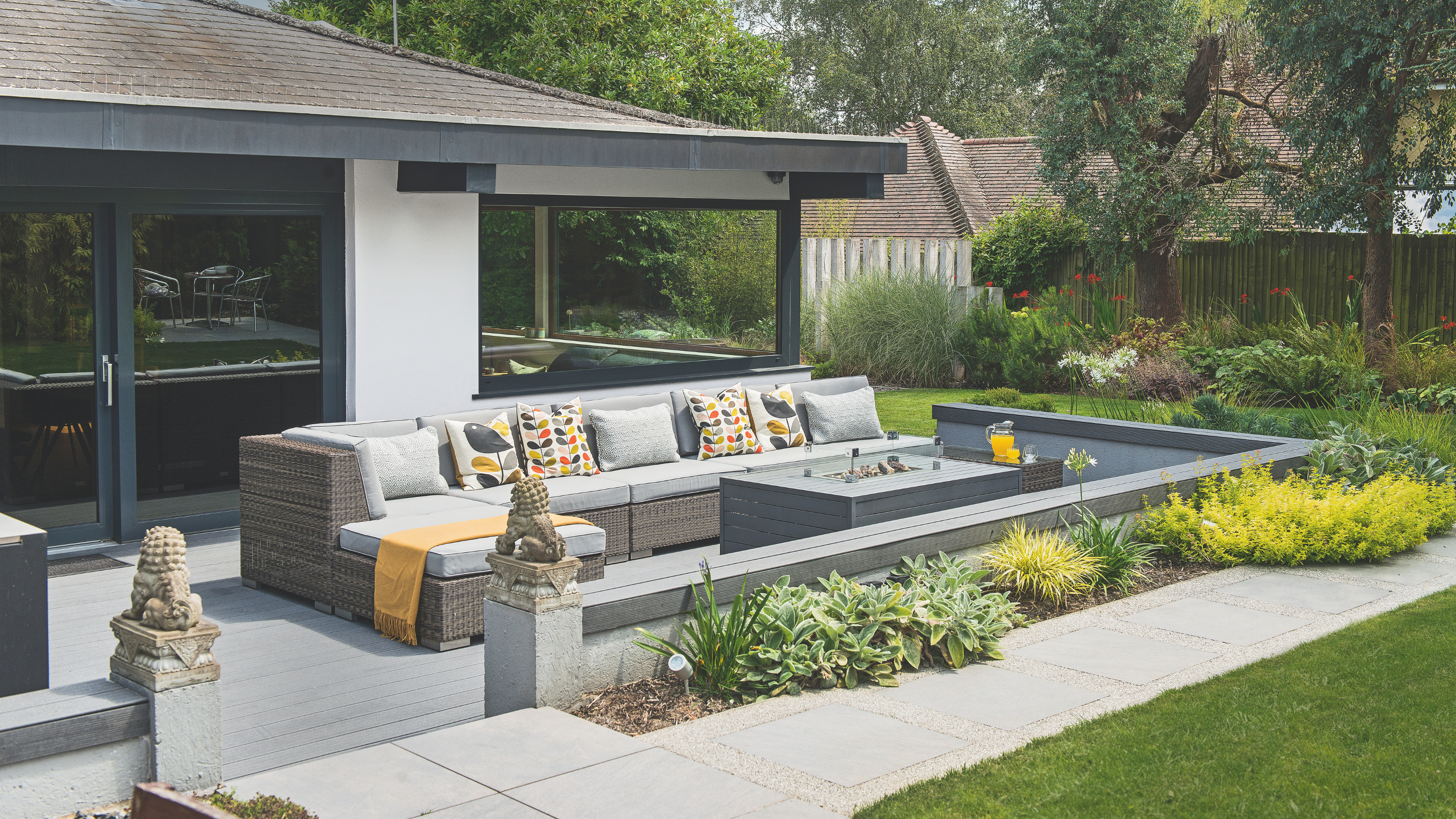 patio with garden furniture, flower beds and borders outside a bungalow.