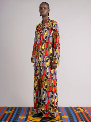 A beautifully, pattern-filled pyjiama in tones of red, black, yellow, and white is worn by a model in a dressing room.