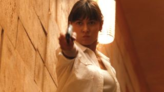 Olga Kurylenko fiercely aims a gun in front of her in Quantum of Solace.