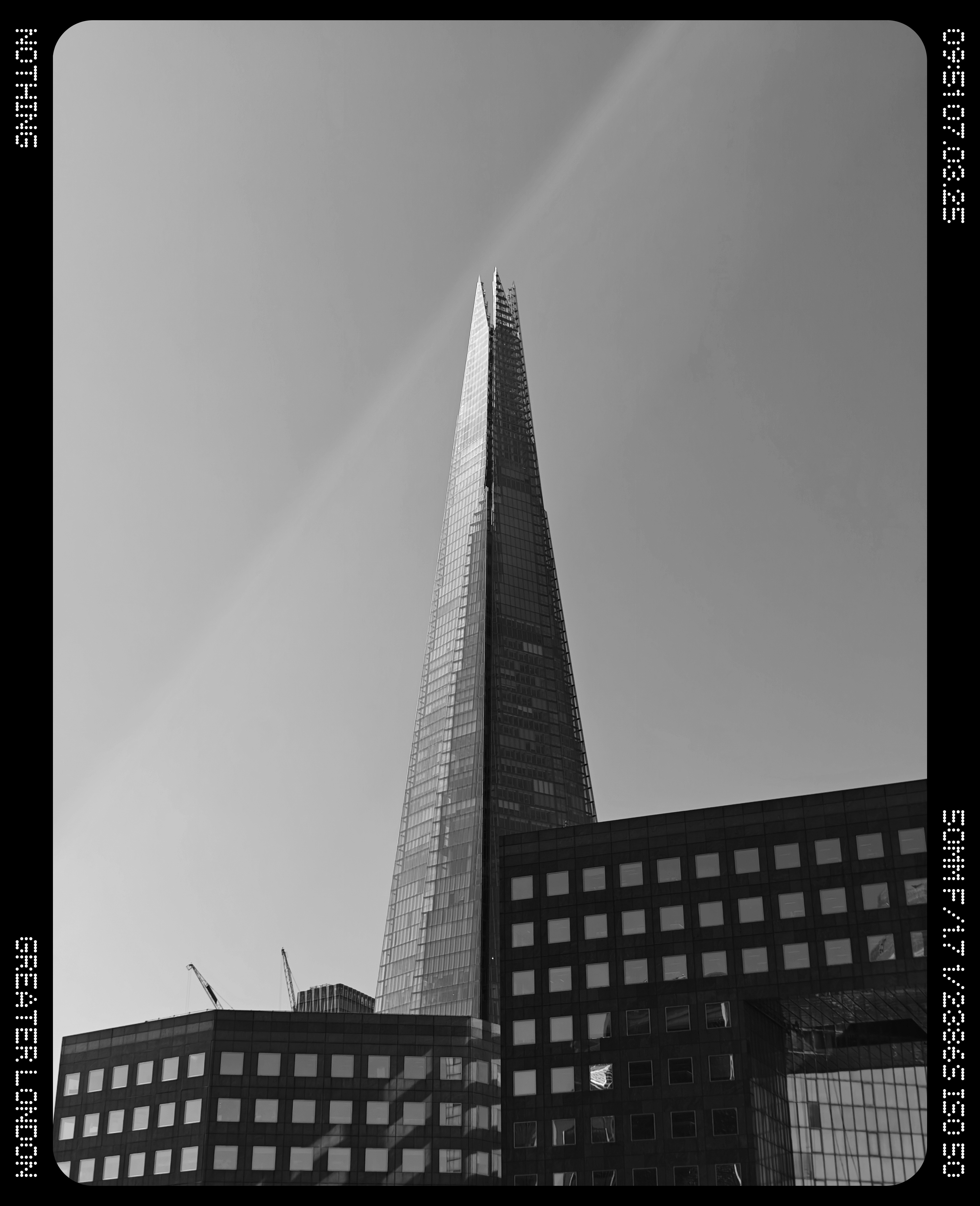 The shard rising above some buildings in front of a clear sky