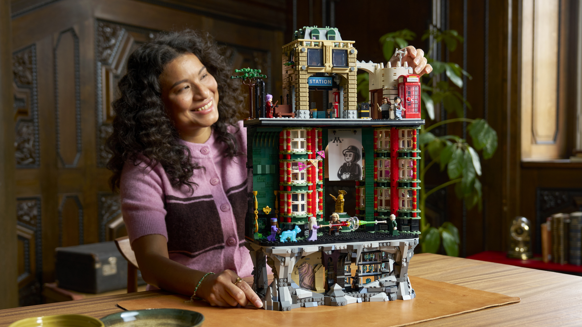 A woman smiles while placing a final piece on the Lego Ministry of Magic set