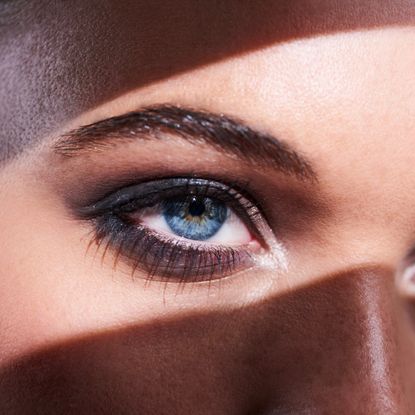 close-up of a woman's blue eyes with a shadow running across her face