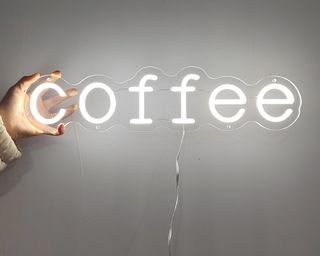 A white neon coffee bar sign on clear acrylic