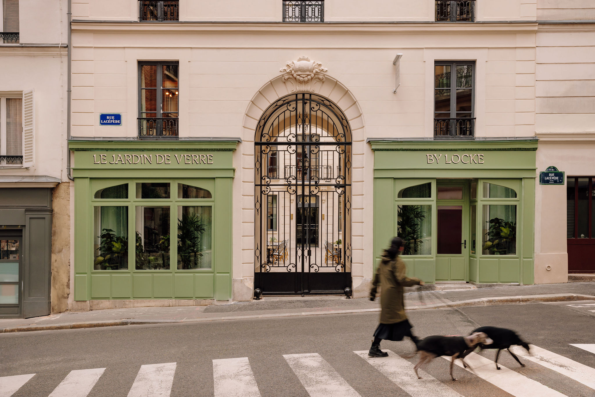 A Parisian hotel's exterior features an ornate, engraved surface painted in buttery and green tones, while inside, trailing plants and Art Deco furniture set the tone.