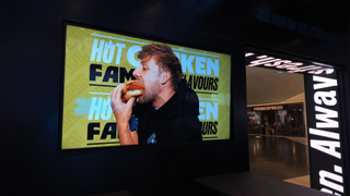 Digital displays showcasing people eating in a food court. 