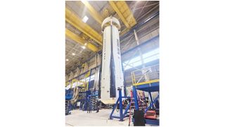 a white rocket booster is suspended a few feet from the ground inside a huge hangar