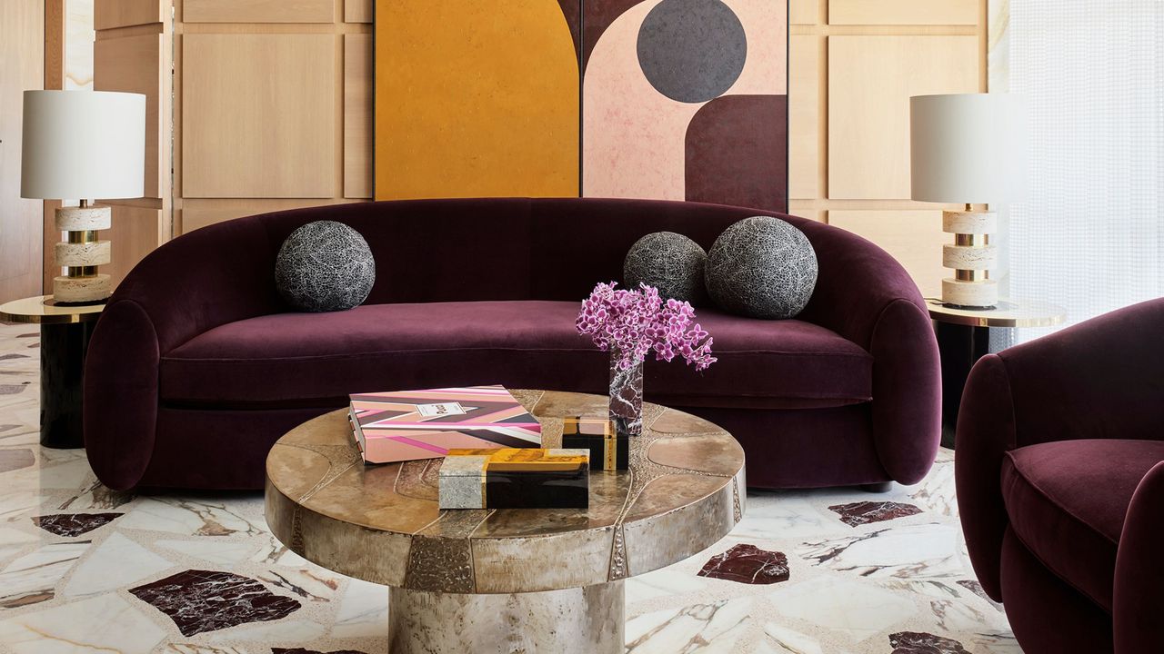 burgundy sofa in living room with marble table and floors