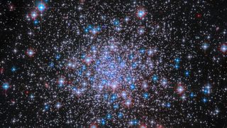 Thousands of glowing white and blue stars with a denser cluster towards the center of the image. 