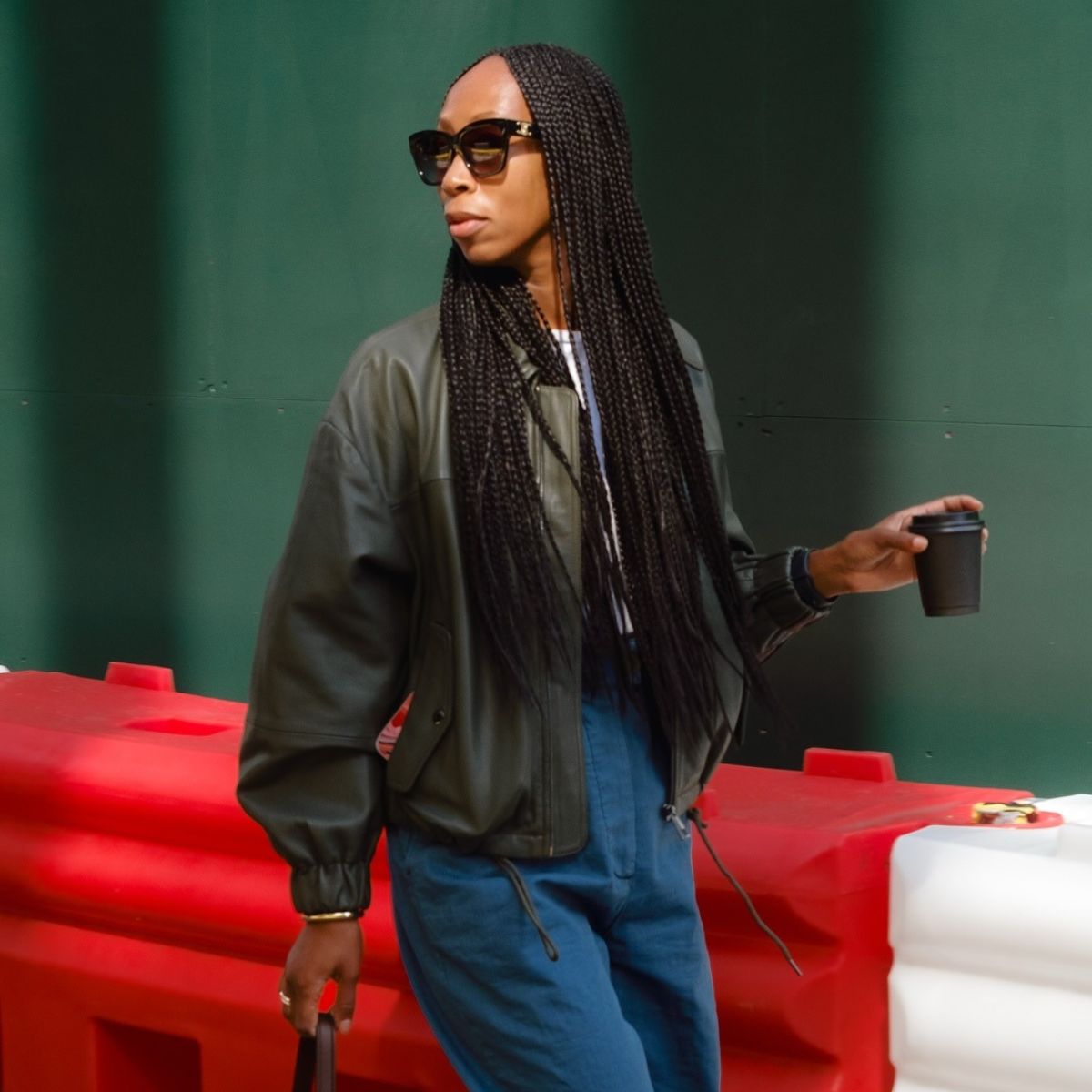 Woman wears green bomber leather jacket, blue trousers