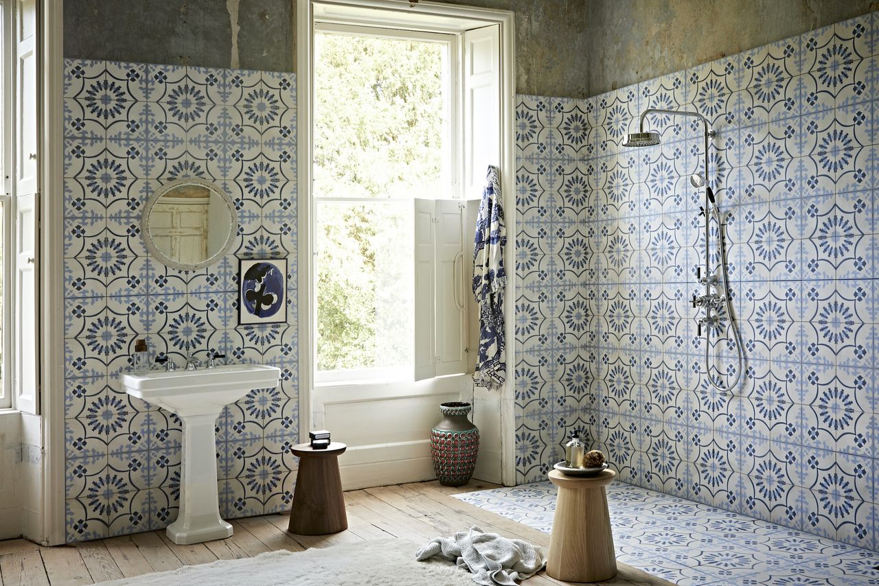 Blue and white tiled bathroom with walk-in shower, wooden benches and chrome shower