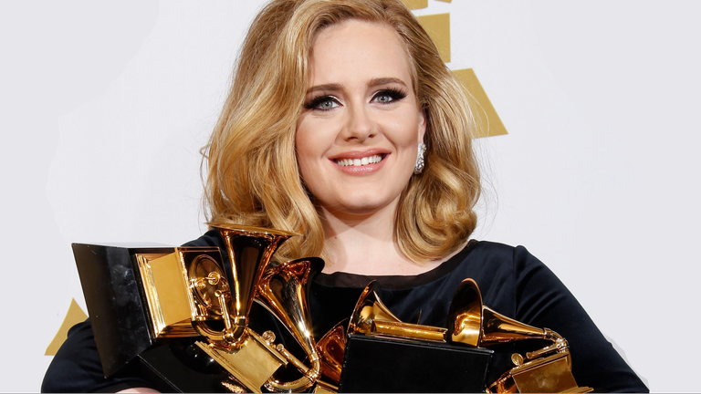 Smiling Adele holding a few Grammy awards