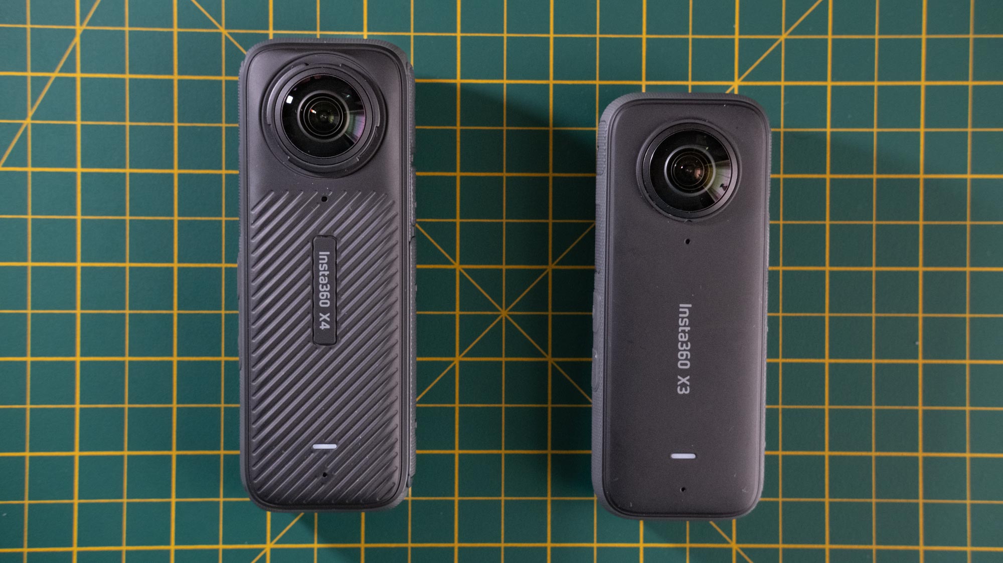 A photo of the Insta360 X4 side by side with the Insta360 X3 on a cutting mat