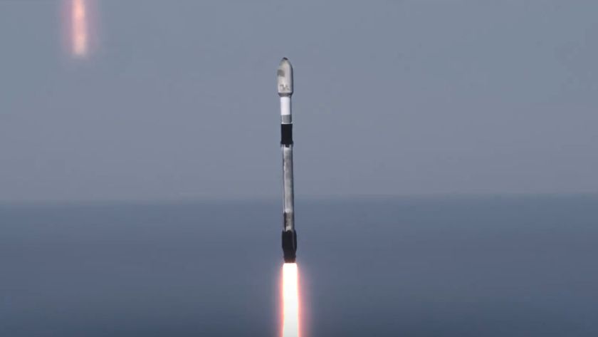 A used black and white SpaceX rocket launches with the ocean horizon in the background.