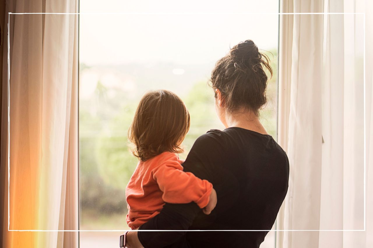 mum holding toddler and looking out of the window