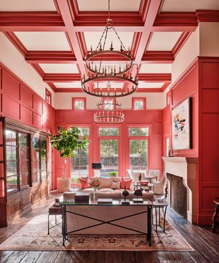 Grand living space with double height ceiling, red and pink painted walls and ceiling, seating space around fireplace