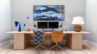 home office with grey wallpaper, light wood large desk, and two orange chairs