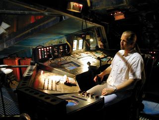 Lee Stringer sits in space ship's control bridge