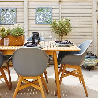 Outdoor dining area with plants and set tablemats, white painted garden fence with blue embellishments