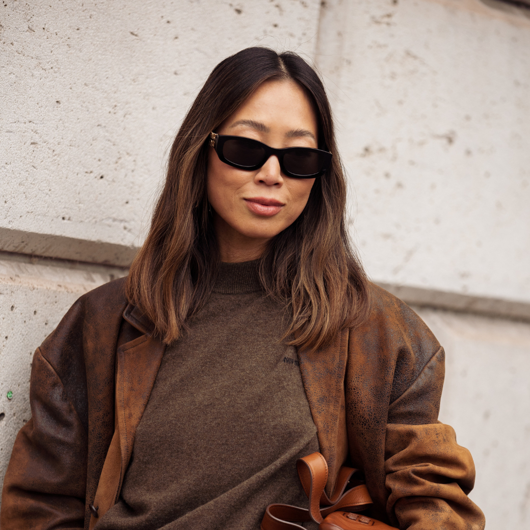 Aimee Song wears brown jumper, leather jacket, grey pants, brown bag outside MiuMiu show during the Womenswear Spring Summer 2026 as part of Paris Fashion Week on October 06, 2025 in Paris, France