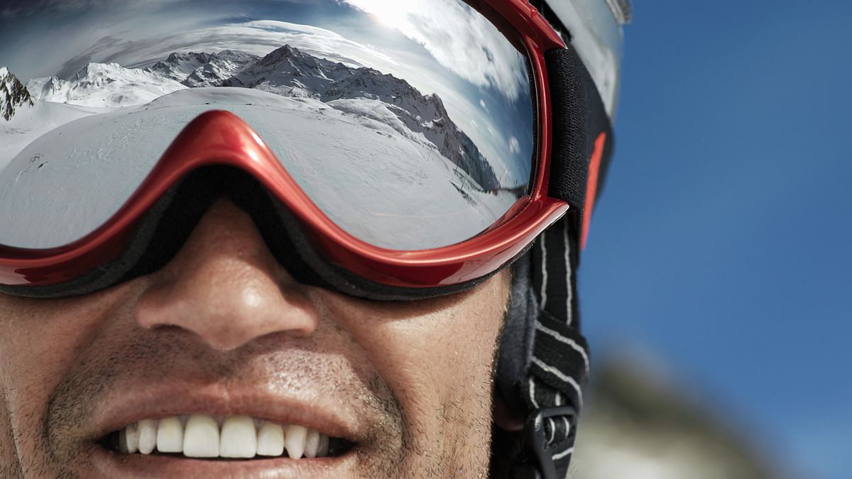 A close up of mountains reflected in a man&#039;s ski goggles