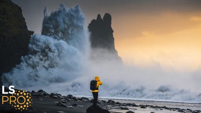 A massive wave hits a cliff on the coast of Iceland at sunset.
