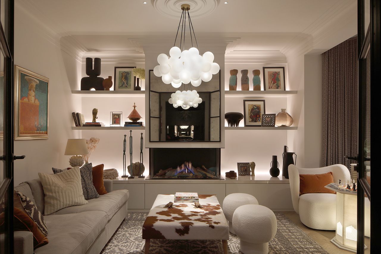 A reception room with a statement ceiling lamp and recessed shelves with lighting