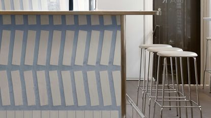 A bar with a white tiled wall with oversized, chunky blue grouting joints