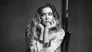 Mono photograph of a female subject sat on a chair in a photo studio, looking bored, shot on a Leica SL3